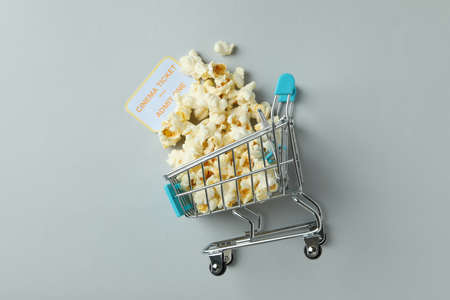 Shop trolley with popcorn and ticket on light gray background.の写真素材