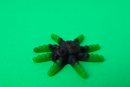 Gummy candy in the form of spider on green background.の写真素材