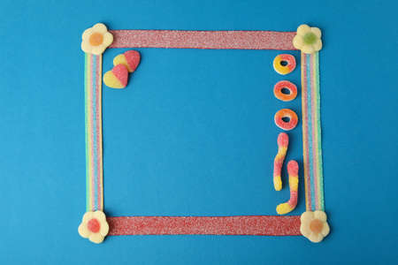 Photo frame made of gummy candies on blue background, space for text.の写真素材