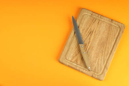 Cutting board with knife on orange background.の写真素材