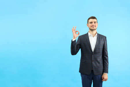 Young businessman show ok sign on blue background.の写真素材