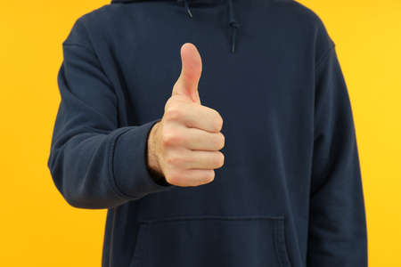 Man in hoodie shows thumbs up sign, close up.の写真素材