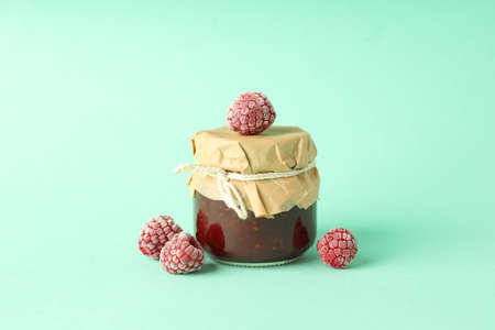 Jar of raspberry jam with ingredients on mint backgroundの写真素材