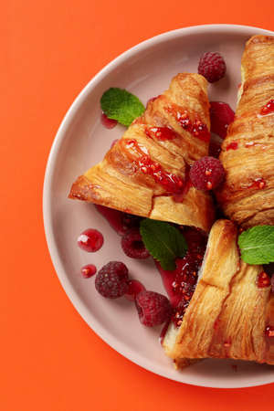 Plate with croissants with raspberry jam on orange backgroundの写真素材