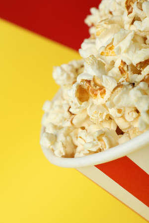 Striped paper cup with popcorn on two tone background.