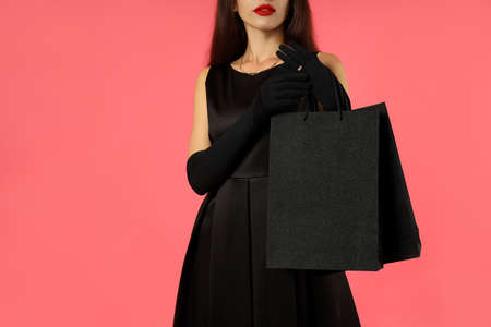 Attractive girl in black dress with paper bags on pink background.の写真素材