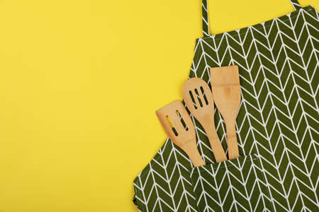 Apron with utensils on yellow background, space for text.の写真素材