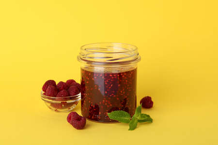 Jar of raspberry jam with ingredients on yellow backgroundの写真素材