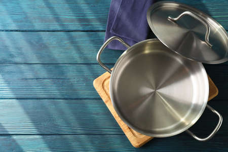 Empty metal pot on cutting board on wooden table.の写真素材