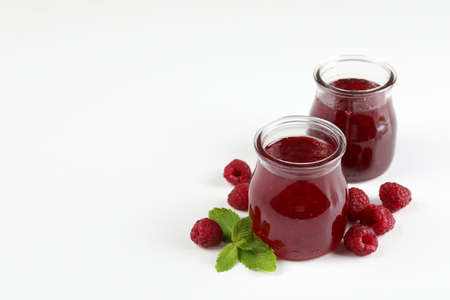 Jars of raspberry jam with ingredients on white backgroundの写真素材