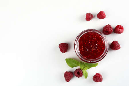 Jar of raspberry jam with ingredients on white backgroundの写真素材