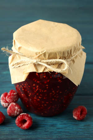 Jar of raspberry jam with ingredients on wooden background