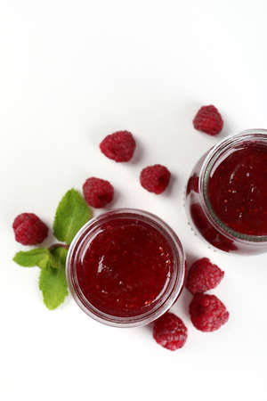 Jars of raspberry jam with ingredients on white backgroundの写真素材
