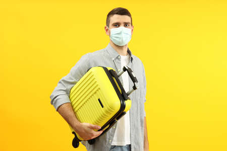 Traveling concept during virus with young man on yellow background.の写真素材