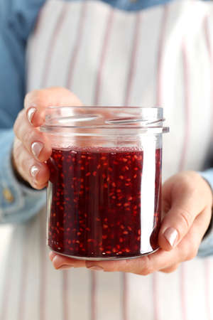 Woman holding jar of raspberry jam in hands, close upの写真素材