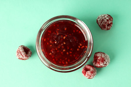 Jar of raspberry jam with ingredients on mint backgroundの写真素材