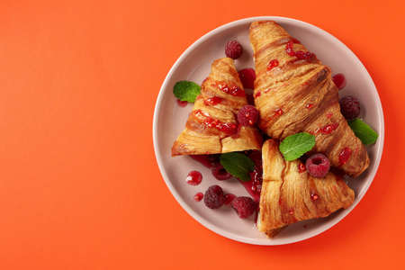 Plate with croissants with raspberry jam on orange backgroundの写真素材