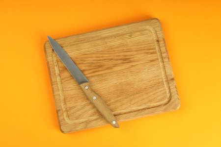 Cutting board with knife on orange background.の写真素材