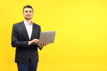 Businessman with laptop on yellow background, space for text.の写真素材