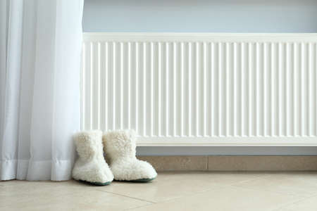 Concept of heating season with knitted boots near radiator.の写真素材