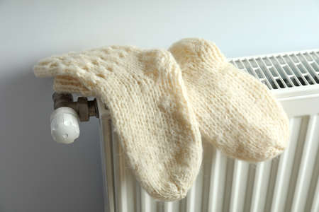 Concept of heating season with knitted socks on radiator.の写真素材
