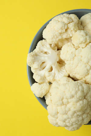 Fresh juicy cauliflower slices in bowl on yellow backgroundの写真素材
