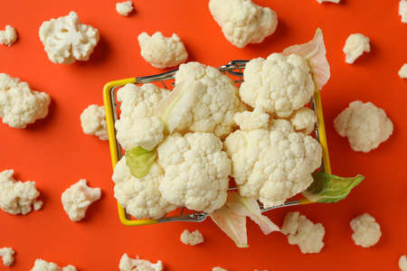 Slices of fresh juicy cauliflower in basket on orange background
