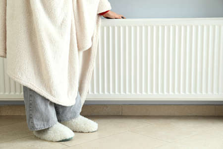Concept of heating season with girl standing near radiator.