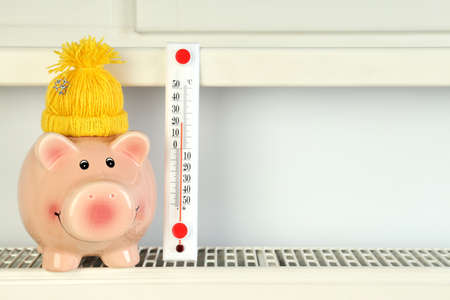 Concept of heating season with piggy bank on radiator.の写真素材