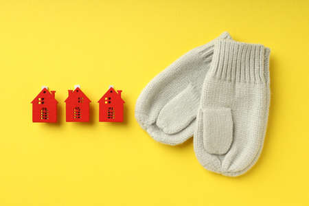 Concept of heating season with mittens and red houses on yellow background.の写真素材