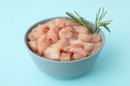 Pieces of raw chicken fillet in bowl on blue backgroundの写真素材