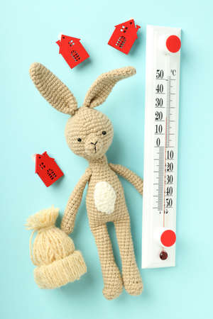 Concept of heating season with toy rabbit on blue background.