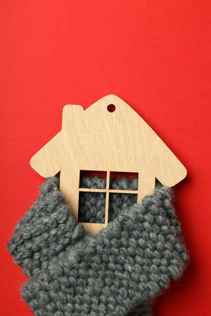 Wooden house with knitted scarf on red background.の写真素材