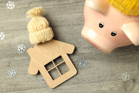 Concept of heating season with piggy bank on gray textured background.
