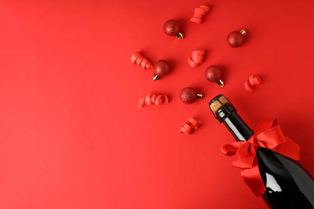 Champagne bottle with bow, and baubles on red background.の写真素材
