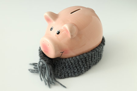 Piggy bank with knitted scarf on white background.の写真素材