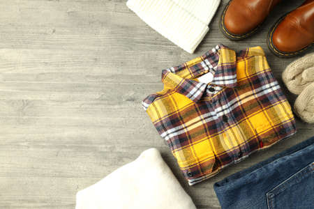 Concept of winter clothes on gray wooden table.