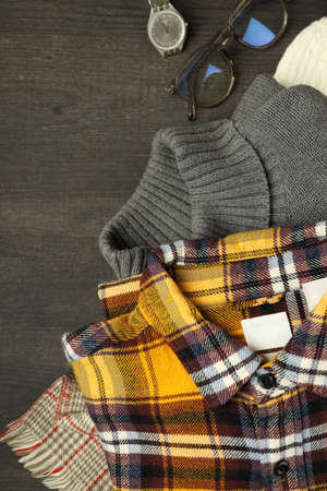 Concept of winter clothes on dark wooden table.
