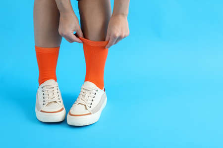 Woman in sneakers pulls up a sock on blue backgroundの写真素材