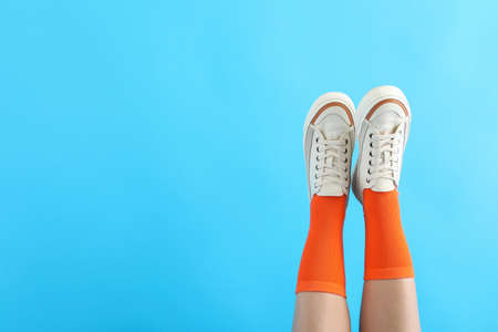 Female legs in orange socks and sneakers on blue backgroundの写真素材