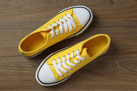 Pair of yellow sneakers on wooden background