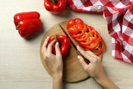 Woman hands cut bell pepper on wooden boardの写真素材
