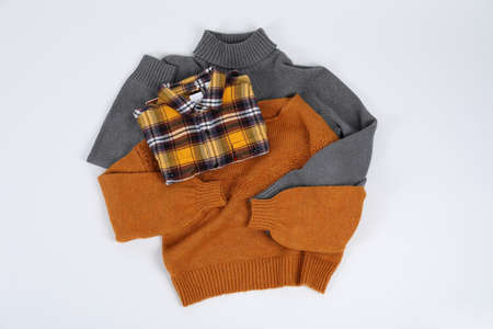 Sweaters with shirt on white background, top view.