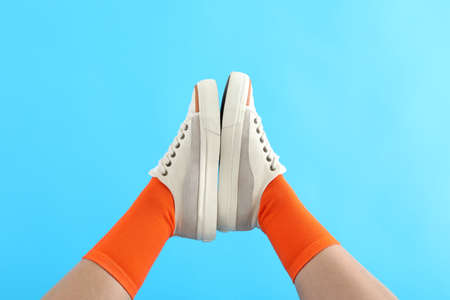Female legs in orange socks and sneakers on blue backgroundの写真素材