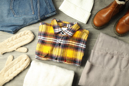 Concept of winter clothes on gray wooden table.