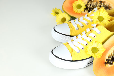 Yellow sneakers with flowers and papaya on light gray backgroundの写真素材
