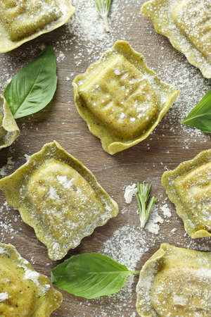 Raw ravioli with flour and basil on wooden backgroundの写真素材