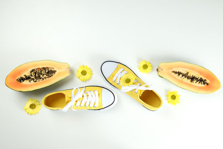 Yellow sneakers with flowers and papaya on white backgroundの写真素材