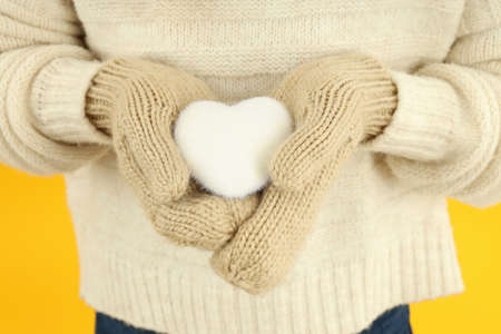Girl holds decorative snow heart on yellow background.の写真素材
