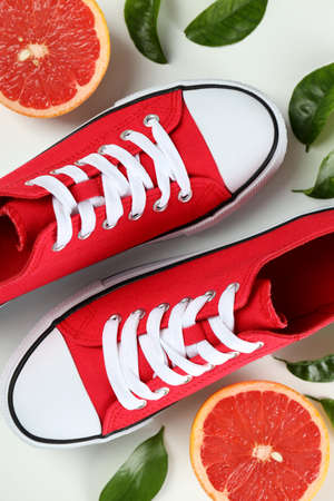 Red sneakers and grapefruit with leaves on white background